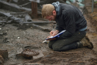 Wood specialist Mike Bamforth examining the base of a two-piece wooden bucket.